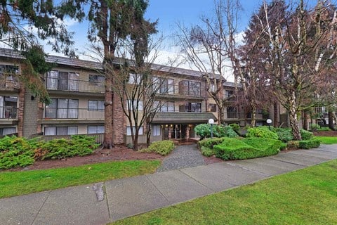 front view of an apartment building with a sidewalk and grass