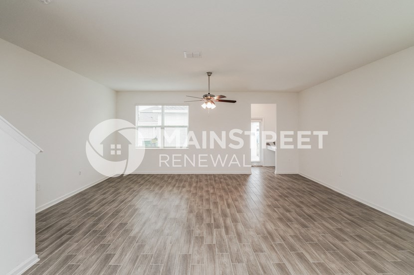 a renovated living room with hard wood floors and a ceiling fan