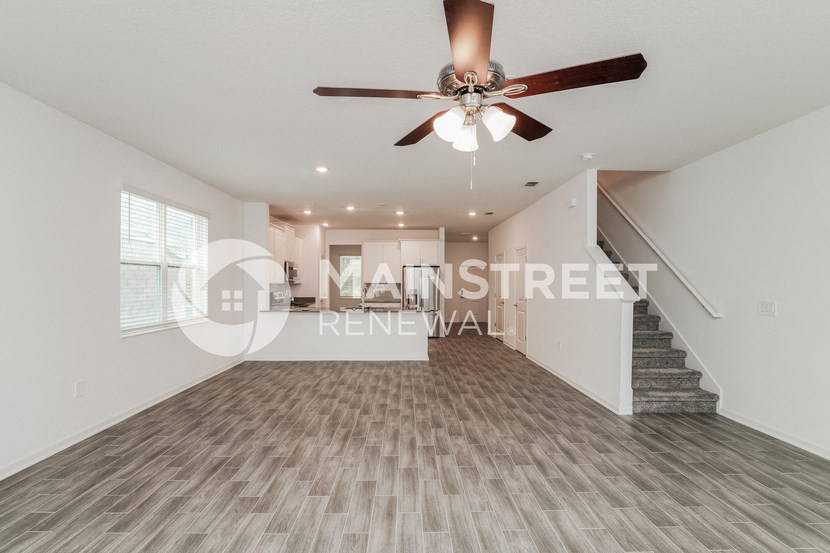 a renovated living room with stairs and a ceiling fan