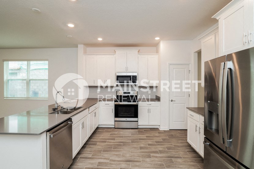 a large kitchen with white cabinets and stainless steel appliances