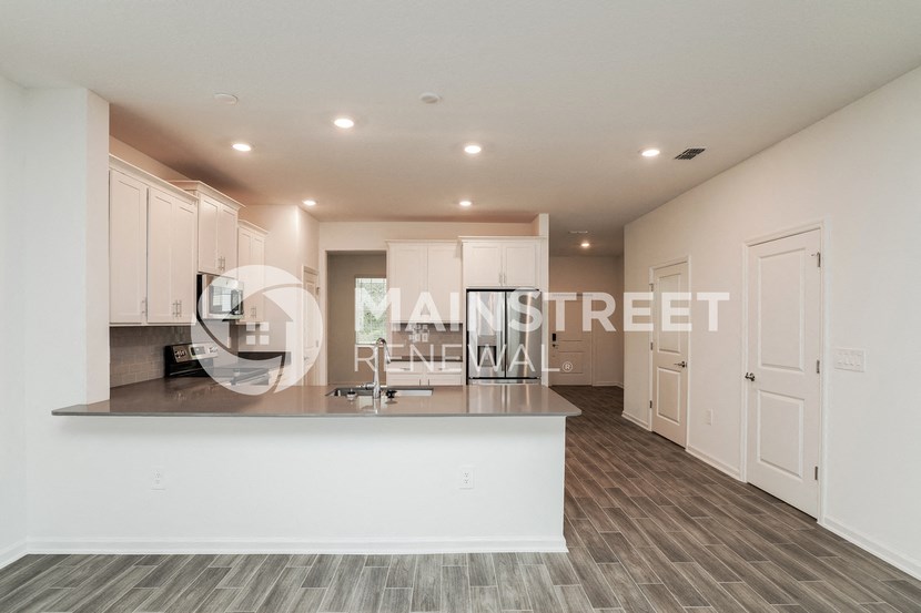 a kitchen and living room with white cabinets and a counter top