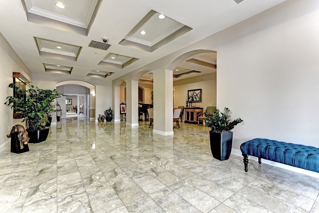 a large lobby with a blue bench and potted plants