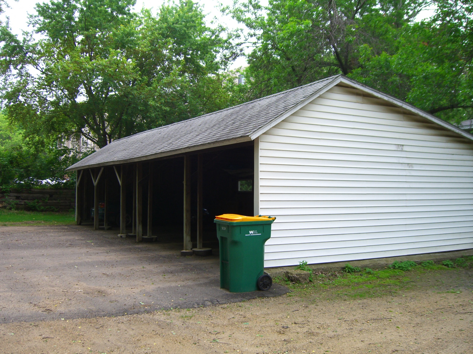 a garage with a green trash can in front of it