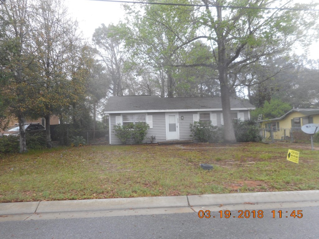 the front of a white house with a yard and trees