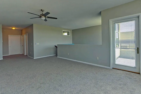 an empty living room with a ceiling fan and a window