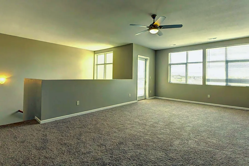 an empty living room with a ceiling fan and a window