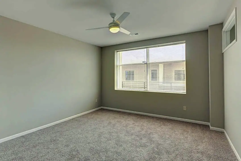 an empty room with a ceiling fan and a window