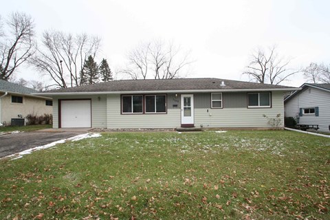 the front of the house with a lawn and a white garage door