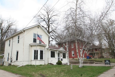 a white house with an flag in front of a red house
