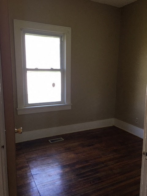 a small room with a window and wooden floors
