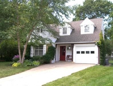 A white house with a red door and a garage.