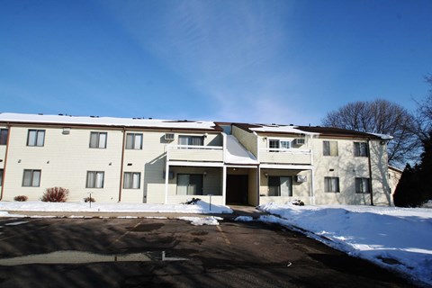 A large apartment building with a parking lot in front.