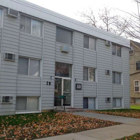 a white apartment building with a sidewalk in front of it