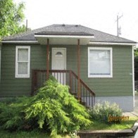 A green house with a white door and windows.