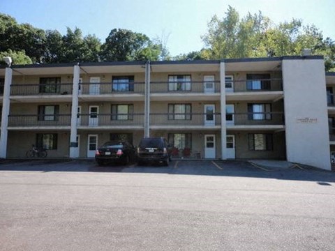 A parking lot in front of a multi-story apartment building with two cars parked.