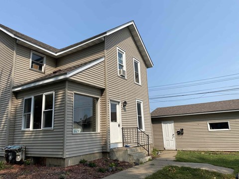 the front of a house with a white door and a driveway