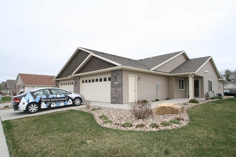 A car with the text "MATRIX MANAGEMENT" on it is parked in front of a house.