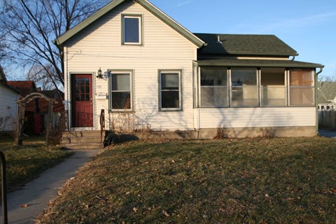 a white house with a red door and a sidewalk