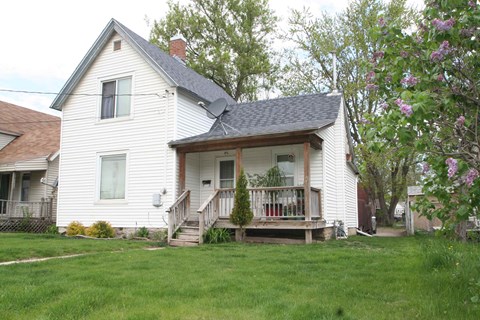 a white house with a porch on a lawn