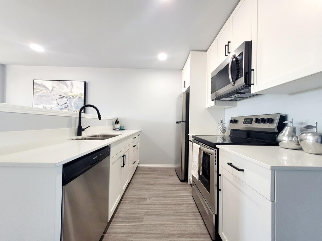 A modern kitchen with white cabinets and stainless steel appliances.