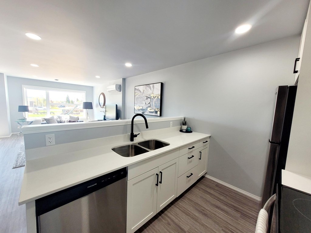 A modern kitchen with a stainless steel dishwasher and white countertops.