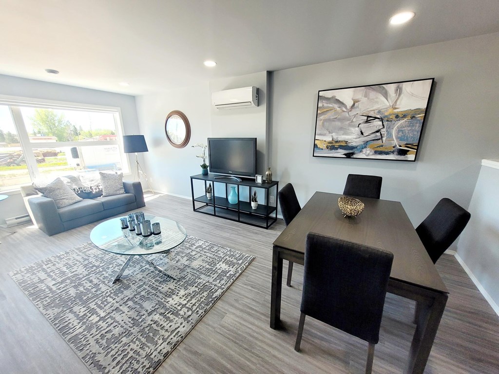 A modern living room with a glass coffee table and a grey sofa.