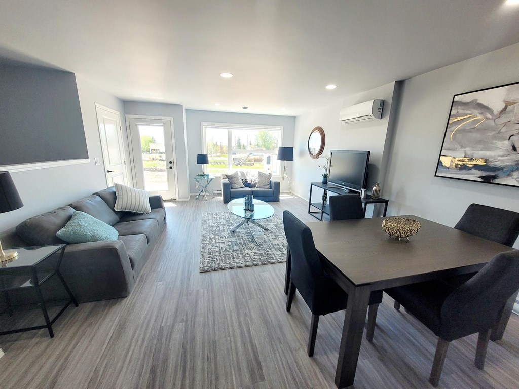 A modern living room with a grey sofa, black chairs, and a wooden coffee table.
