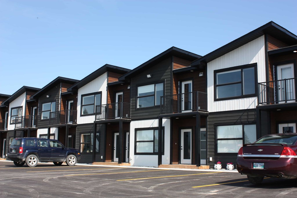 A row of townhouses with cars parked in front.
