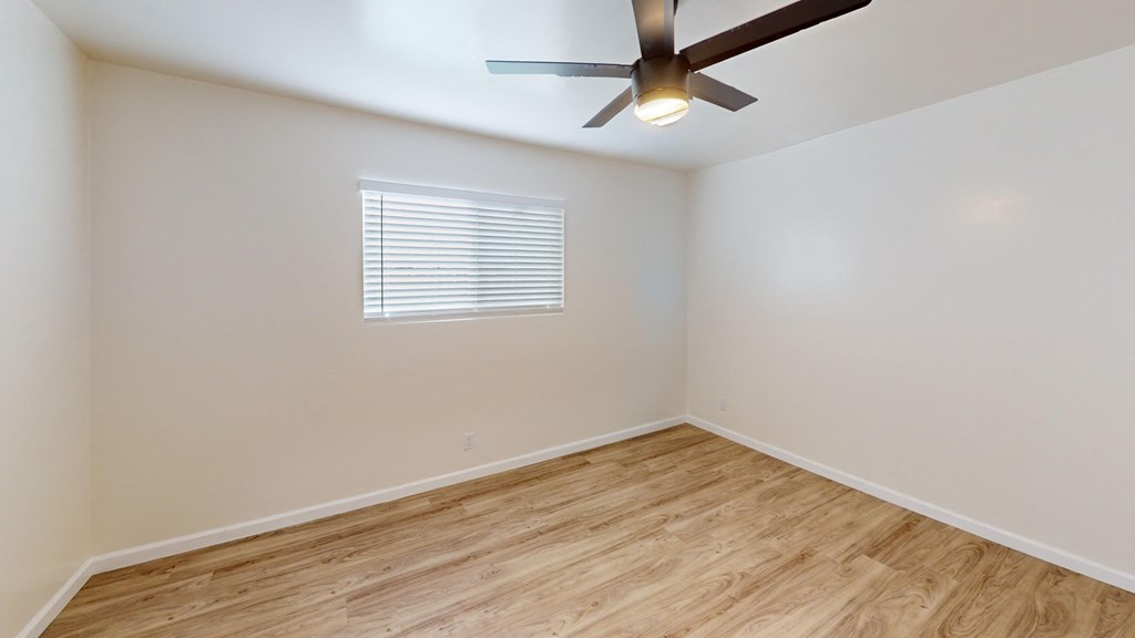 an empty room with a ceiling fan and wood floors