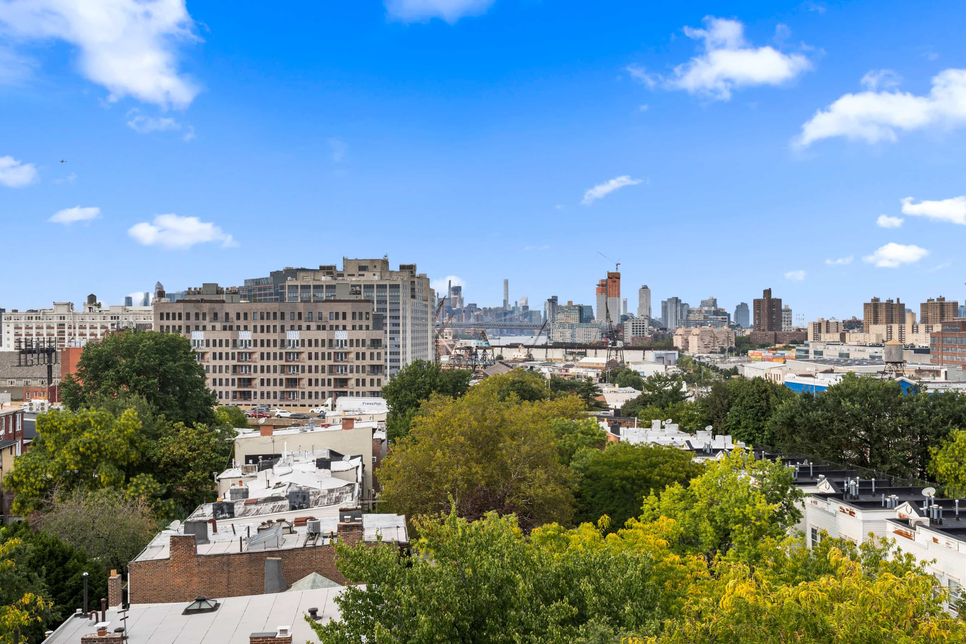 A cityscape with buildings and trees in the foreground.