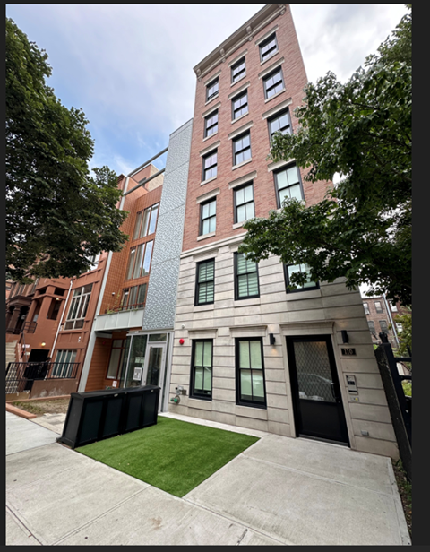 A modern building with a red brick facade and a grey concrete structure in front.