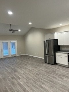 an empty living room with a kitchen and a refrigerator