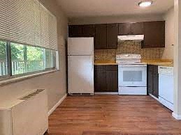 A kitchen with white appliances and wooden floors.
