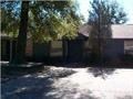 a house with trees and a dirt road in front of it