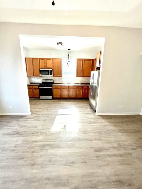 an empty kitchen with wooden cabinets and stainless steel appliances