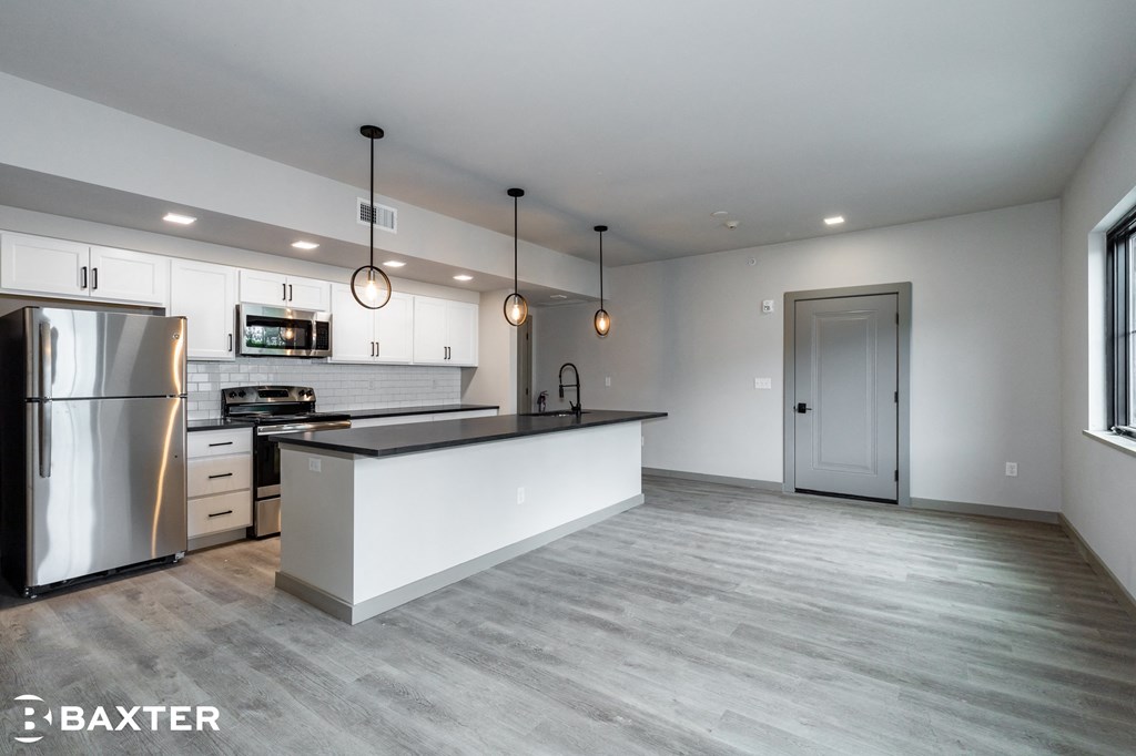 a white kitchen with a large island and stainless steel appliances