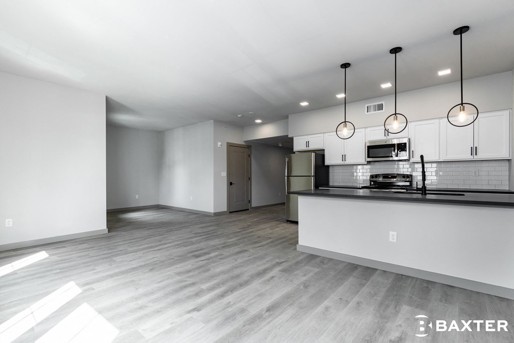 an open kitchen and living room with white cabinets and a counter top