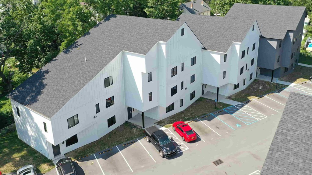 an aerial view of a white building with cars parked in front of it