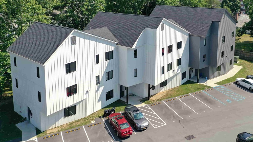 an aerial view of a white building with cars parked in a parking lot