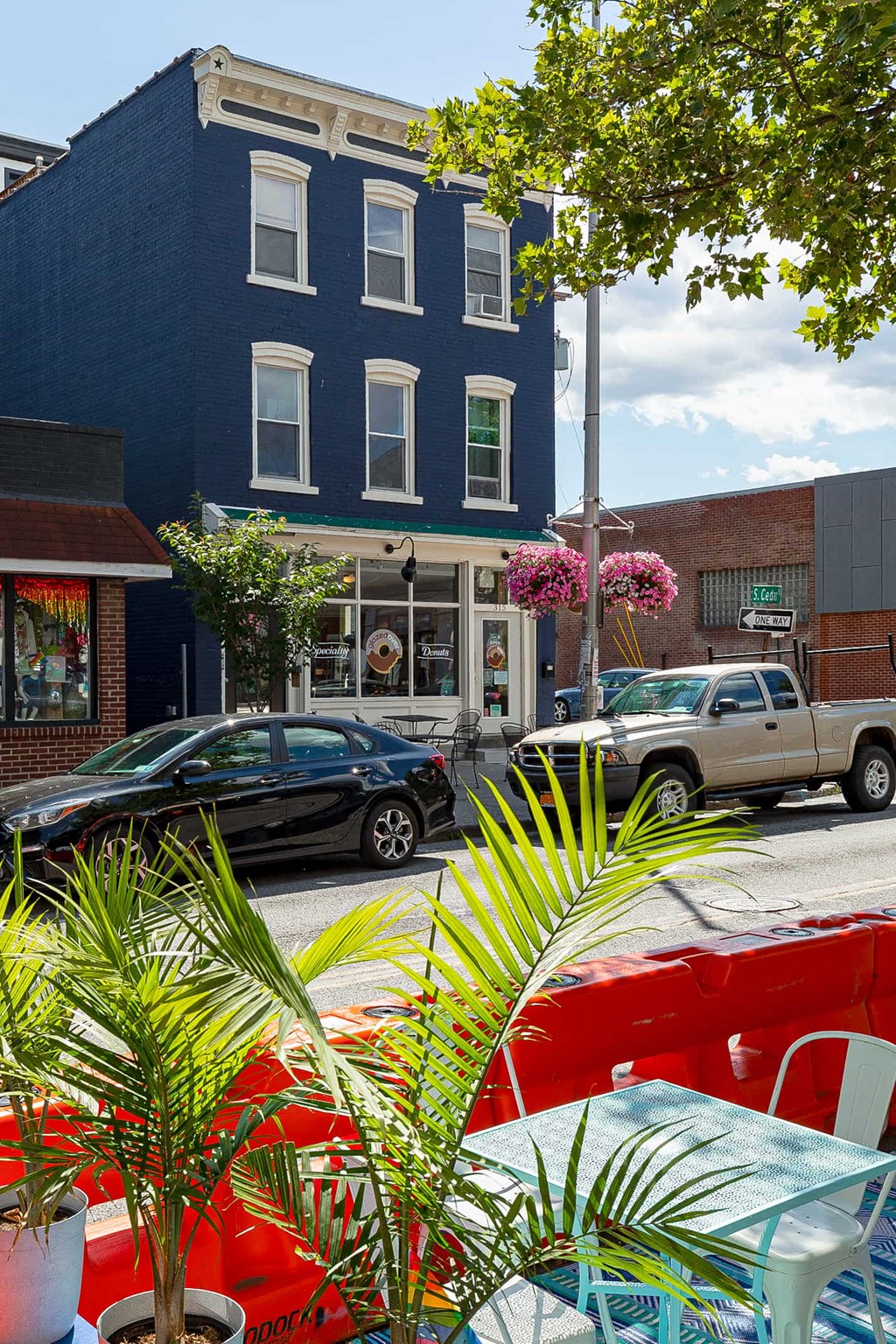 a city street with a blue building and a red car