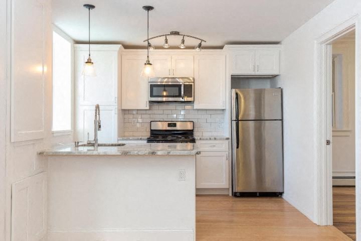 a kitchen with white cabinets and a stainless steel refrigerator