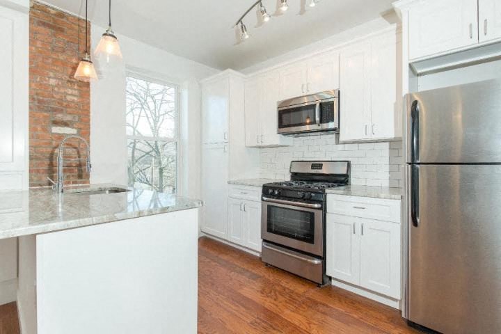 a kitchen with white cabinets and stainless steel appliances