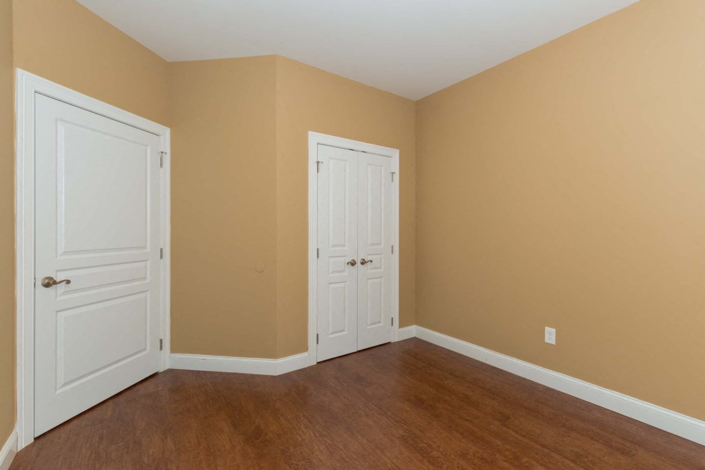 a bedroom with two doors and a wood floor