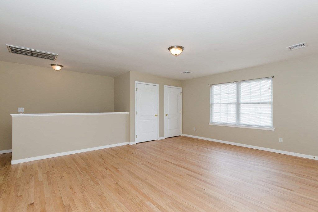 an empty living room with a hardwood floor and a window