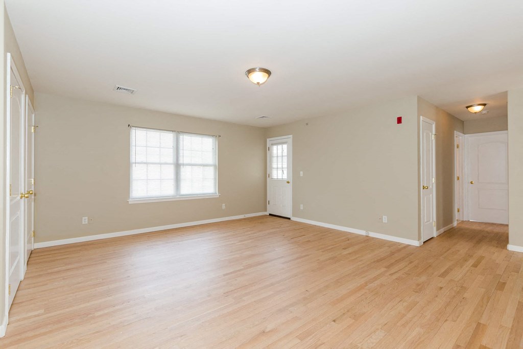 an empty living room with a hard wood floor and a door