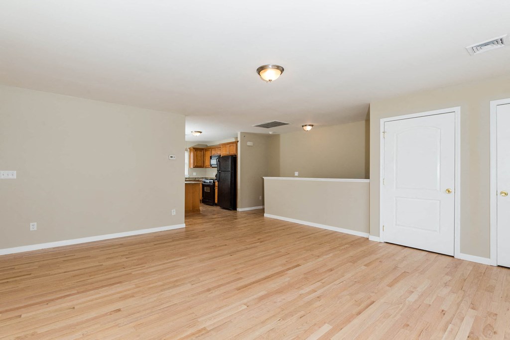 the living room and kitchen of an empty house with wood floors