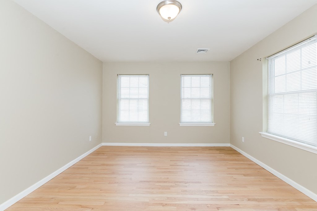 an empty room with wood floors and three windows