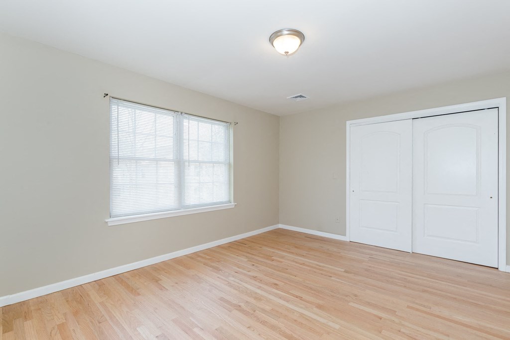 a bedroom with two doors and a window and a wood floor