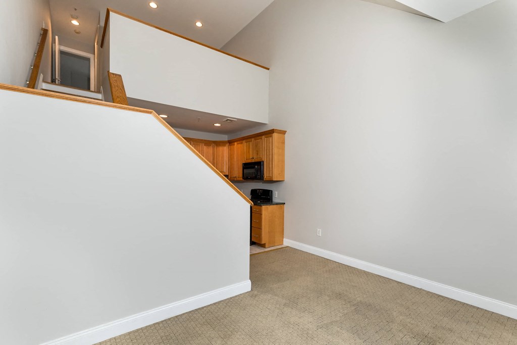 a living room with a white wall and a staircase