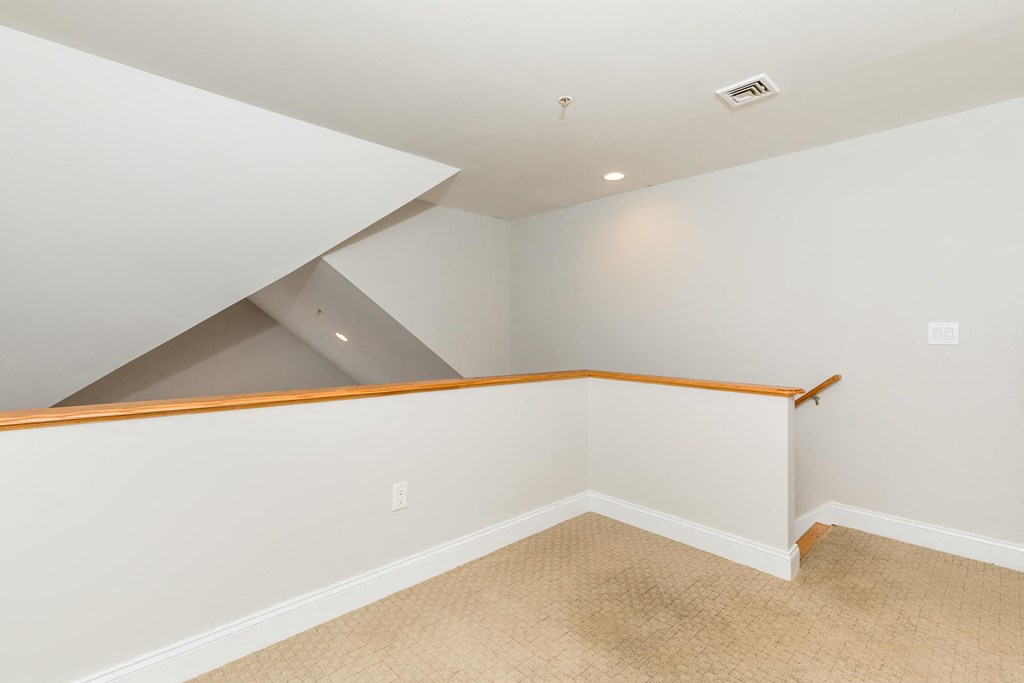 loft area with white walls and a railing and carpeted flooring